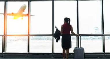 female standing on airport's glass window